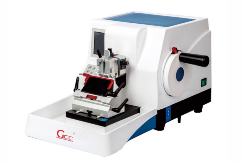 A modern pathology cryostat in a laboratory setting, with a technician preparing a tissue sample for frozen section analysis inside the illuminated freezing chamber.